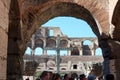 Ruins and stone cross inside the Roman Colosseum, tourists visiting ancient ruins from famous gladiators arena Royalty Free Stock Photo