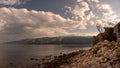 Ruins of stone house on waterfront in sunset, mountains and sea in background