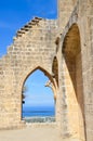 Ruins of the walls of historical Bellapais Abbey with a window that is offering a beautiful view of Cypriot Kyrenia region. The