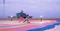 The ruins of West Pier, Brighton, East Sussex, UK. In the foreground, children playing and pavement painted in rainbow stripes.