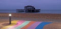 The ruins of West Pier, Brighton, East Sussex, UK. In the foreground, pebble beach and pavement painted in rainbow stripes.