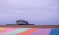 The ruins of West Pier, Brighton, East Sussex, UK. In the foreground, pebble beach and pavement painted in rainbow stripes.