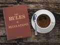 Rules and regulation book and cofee cup on wooden table. Comlience