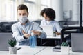 Rules for safety health during coronavirus outbreak. Man in protective mask treat his hands with antiseptic at workplace Royalty Free Stock Photo