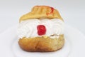 Rum Baba with Cream and a Cherry on a White Plate with a White Background Royalty Free Stock Photo