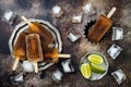 Rum and coke cocktail popsicles with lime juice. Cuba libre homemade frozen alcoholic paletas - ice pops. Overhead, flat lay