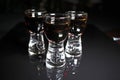 Rum shots. Alcohol shot brown dark rum on black reflective studio background. Isolated black shiny mirror mirrored background for