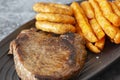 Rump steak dinner, with sweet potato fries and onion rings, on a black oval plate. Royalty Free Stock Photo