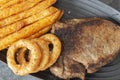 Rump steak dinner, with sweet potato fries and onion rings, on a black oval plate. Royalty Free Stock Photo