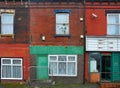 Run down terraced houses on a street in leeds with shabby decaying colourful painted walls and a shop front with an open door