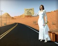 Runaway bride standing on side of road holding sign