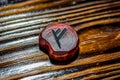 Rune Fehu red color carved from wood on a wooden background