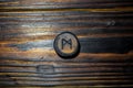 Rune Mannaz Mann carved from wood on a wooden background