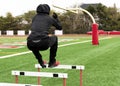 Runer wearing black jumping over track hurdles on a turf field Royalty Free Stock Photo