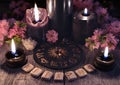 Runes, black candles and zodiac circle against the background with sakura flowers
