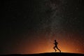 Runner athlete running on the hill with beautiful starry night