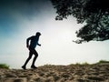 Runner in a blue hooded sweatshirt runs along the beach