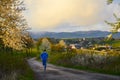 Runner in blue running in spring nature, with village in background. Sport active photo with copy space