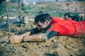 Runner crawling under barbed wire in a test of extreme obstacle race