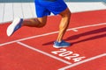 Runner crosses the finish line on a red treadmill with the numbers 2024. New year entry concept, step