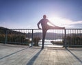 Runner doing stretching exercise on bridge. An active wiry man