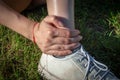 Runner girl outdoors on grass touching painful twisted ankle. Leg injury concept. Vertically Royalty Free Stock Photo