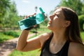 The runner girl quenches her thirst. A young athlete drinks water from a transparent blue bottle Royalty Free Stock Photo