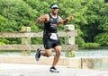 Runner gives peace sign with both hands while crossing a bridge next to a lake