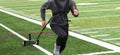 Runner in gray sweatshirt pulling a resistance sled on a turf field Royalty Free Stock Photo