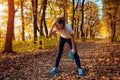 Runner having rest after workout in autumn forest. Tired woman holding water bottle. Sportive active lifestyle Royalty Free Stock Photo