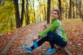 Runner having rest after workout in autumn park. Happy woman holding water bottle. Sportive active lifestyle Royalty Free Stock Photo