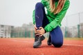 Runner injured leg during training on running track. Woman feels ankle pain holding it with hand. Workout hurt Royalty Free Stock Photo