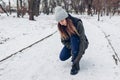 Runner injured leg during training in snowy winter park. Woman feels ankle pain holding it with hand. Exercises outdoors Royalty Free Stock Photo