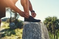 Runner, legs and tie shoelaces on rock, outdoors and prepare for cardio and marathon training. Man, stone and shoe for