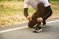 A runner man sitting and tying the shoelace before jogging