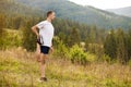 Runner man stretching legs before cross country trail run. Fit male runner exercise training outdoors Royalty Free Stock Photo
