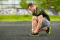 Runner man tying shoelace in the stadium, cross training workout. Sporty male training outside