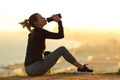 Runner resting hydrating drinking water at sunset