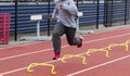 Runner running fazt over yellow mini hurdles on a red track