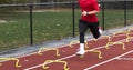 Runner running over yellow mini hurdles at track practice