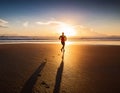 A runner\'s shadow stretching long across a deserted beach at sunset Royalty Free Stock Photo