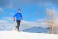 Runner with snowshoes downhill on a sunny day