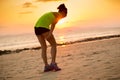 runner with sports injured leg running at sunset sandy beach