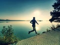 Runner sprints along lake. Freeze sportsman in running pose