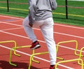 Runner standing over yellow hurdles on a track doing sports training drills