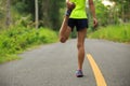 Runner stretching legs before running at morning tropical forest trail Royalty Free Stock Photo