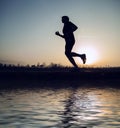 Runner sunset silhouette with mirror in water