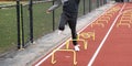 Runner tripping over yellow mini hurdles in lane on a track