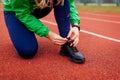 Runner tying shoe laces on running track. Woman training on autumn sportsground. Active healthy sportive lifestyle