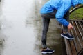 Runner woman tying laces before training in the rain. Marathon.